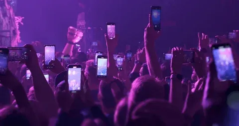 Público grabando con teléfonos durante una presentación de música electrónica.