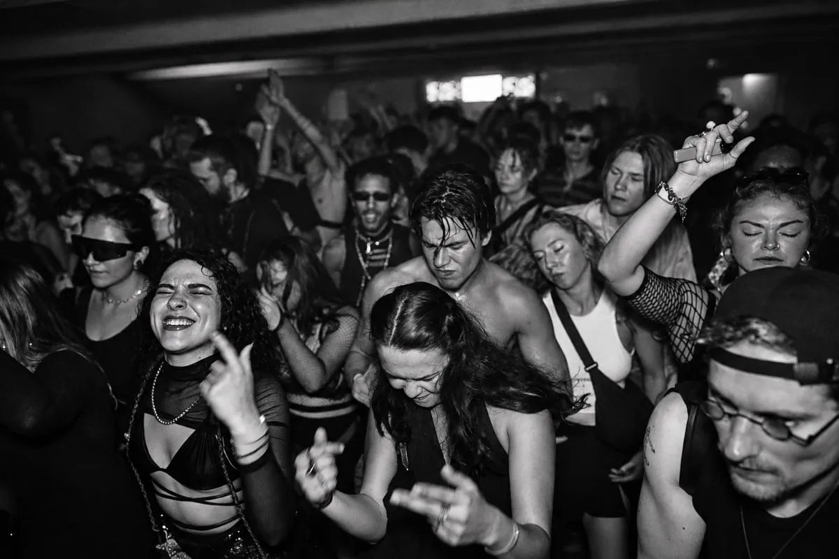Público bailando en una pista de música electrónica sin teléfonos visibles, en un ambiente de club oscuro.