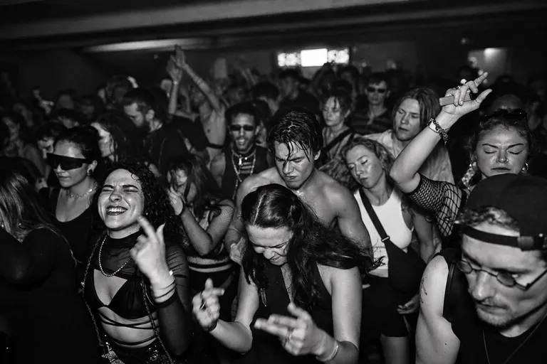 Público bailando en una pista de música electrónica sin teléfonos visibles, en un ambiente de club oscuro.