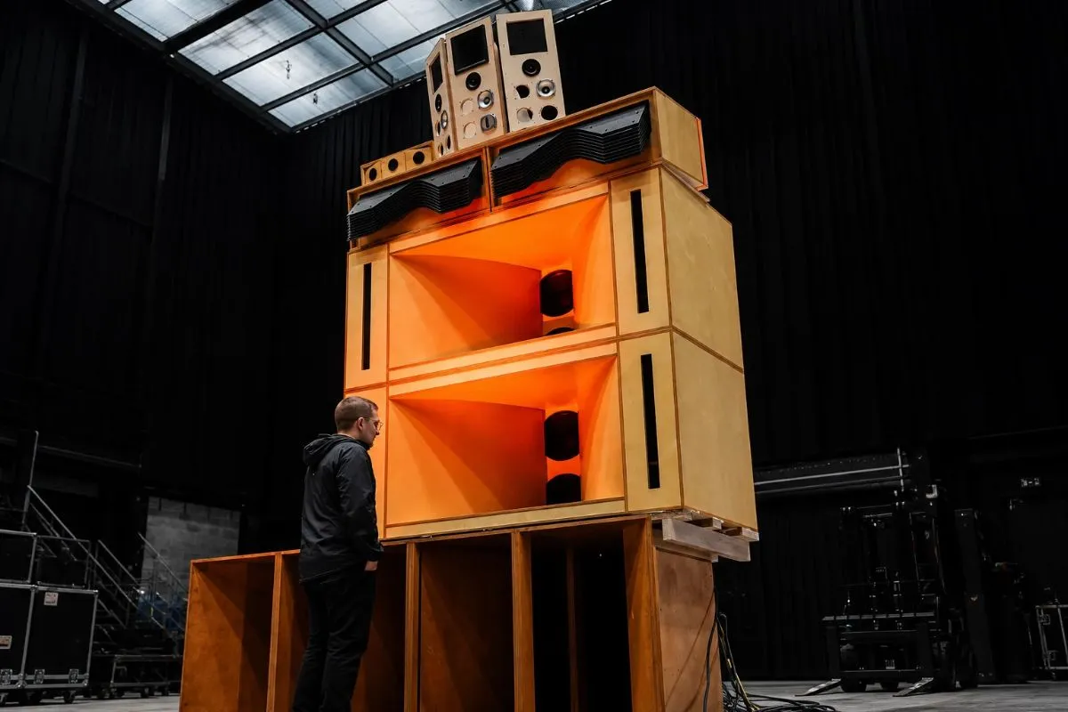 Sistema de sonido hi-fi instalado en un festival de música electrónica, con grandes torres de altavoces alrededor de la pista de baile.